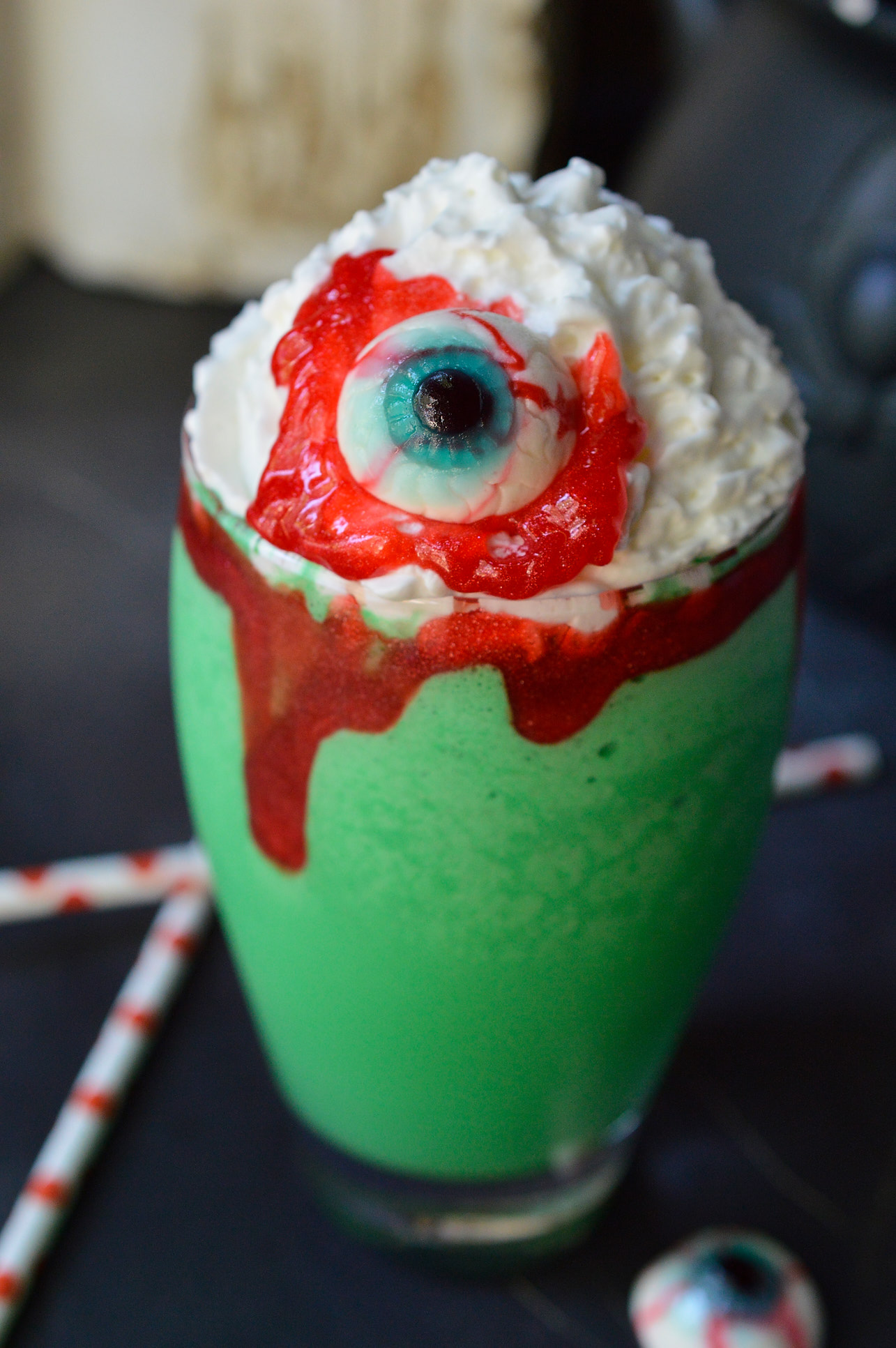 Make this Eye of Toad Halloween Milkshake Recipe for all of your creepy little monsters! This Halloween dessert is made with cookies and cream ice cream, green coloring, whipped cream, red blood gel and topped with a gummy eyeball. This fun recipe is kid approved!