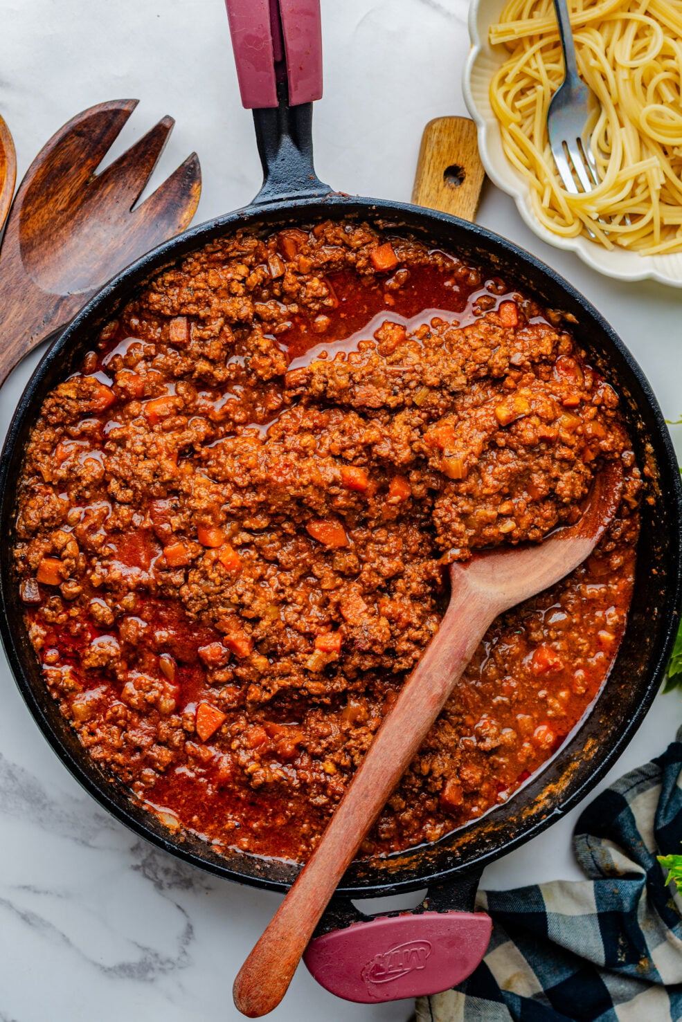 prepared sauce in pan next to bowl of cooked pasta
